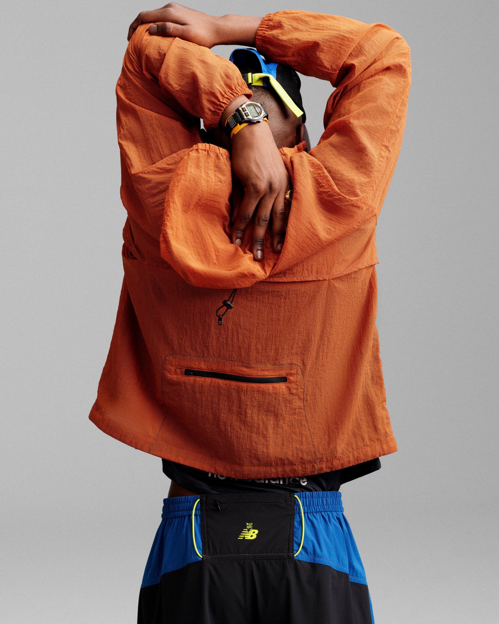 Person wearing the ALD / New Balance Breathable Half-Zip Pullover stretches with arms overhead, facing away from camera.