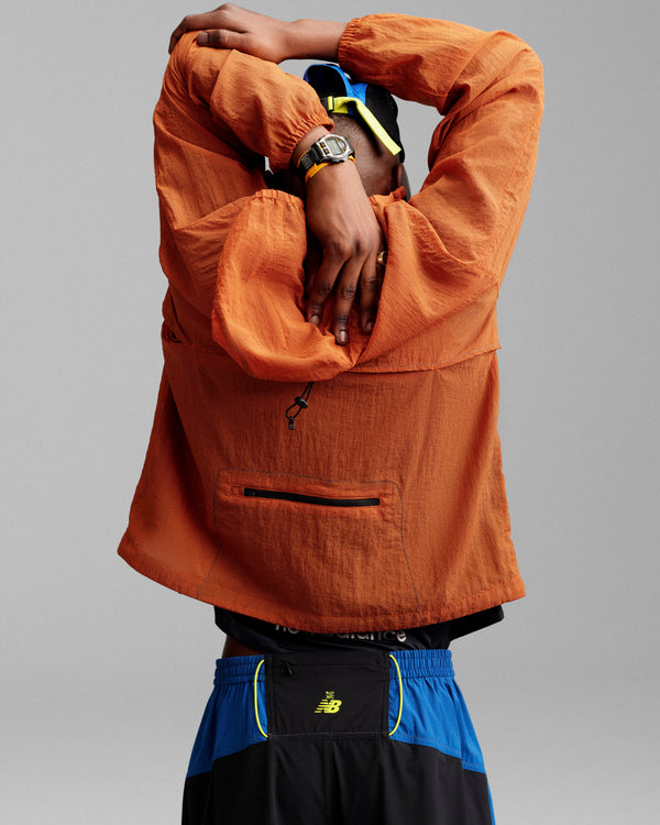 Person wearing the ALD / New Balance Breathable Half-Zip Pullover stretches with arms overhead, facing away from camera.