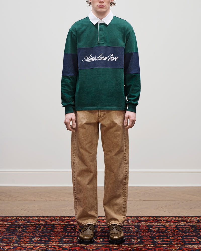 Person wears a green rugby shirt, Relaxed Fit 5-Pocket Denim Pant, and brown shoes on a patterned rug.