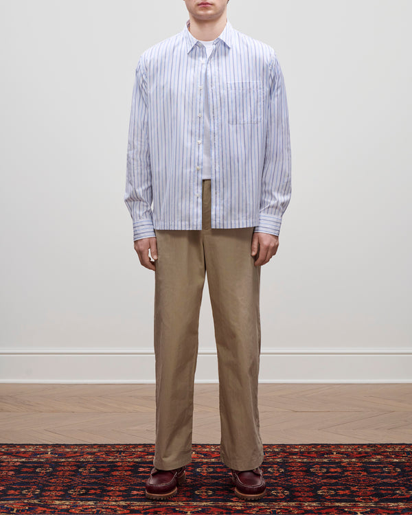 A person wears a Poplin Casual Shirt with tan pants and brown shoes, standing on a patterned rug.