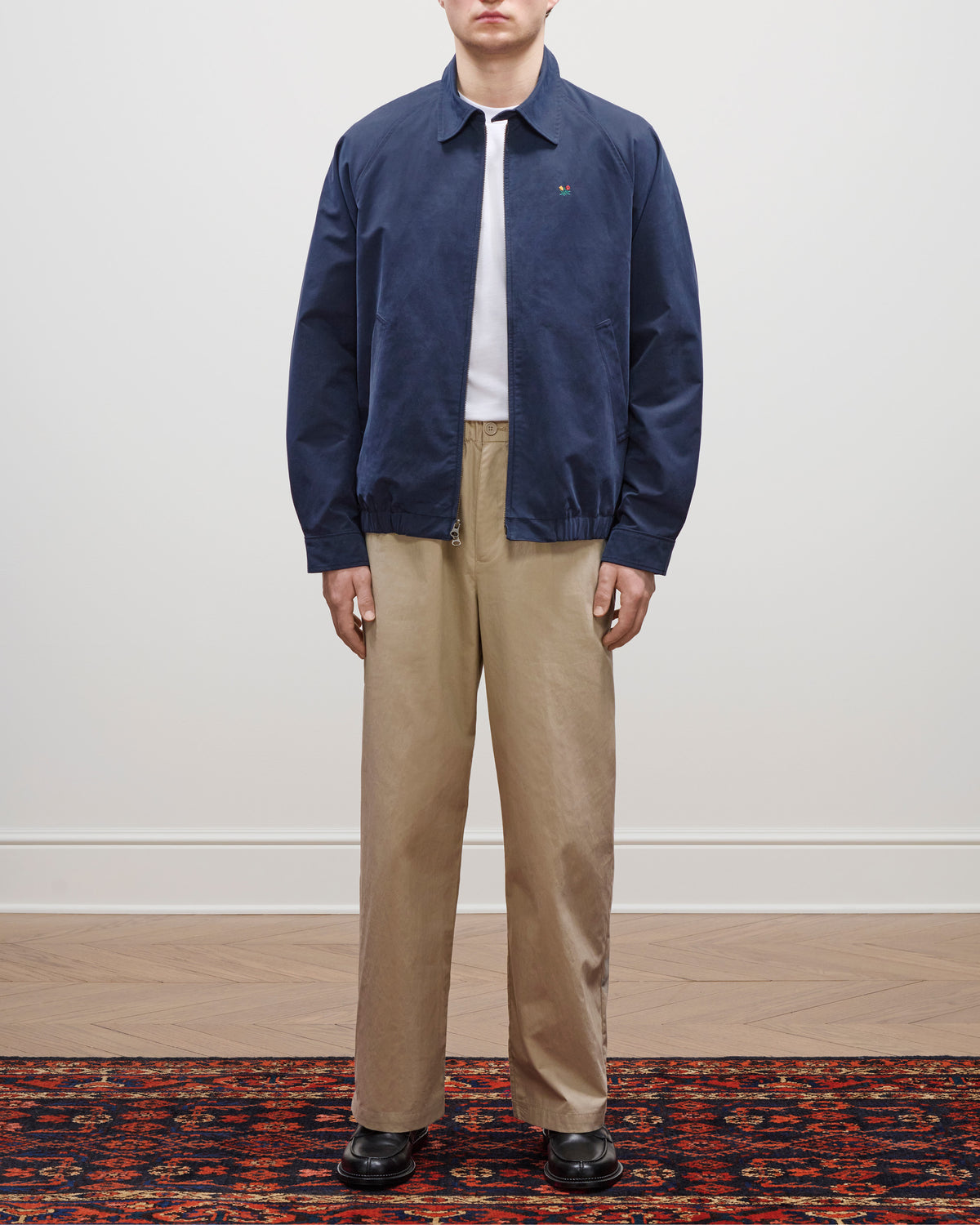 Person wearing a Crest Casual Jacket, white shirt, beige pants, and black shoes stands on a patterned rug.