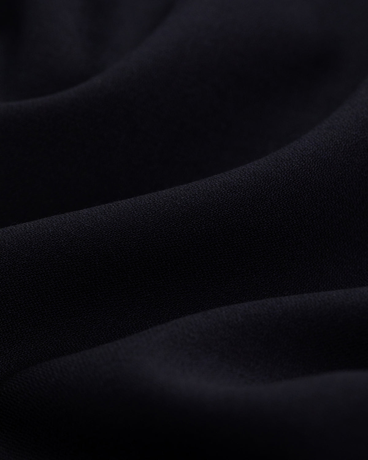 Close-up of Tropical Wool Suit Jacket in black, featuring soft, flowing folds and a smooth, slightly textured surface.