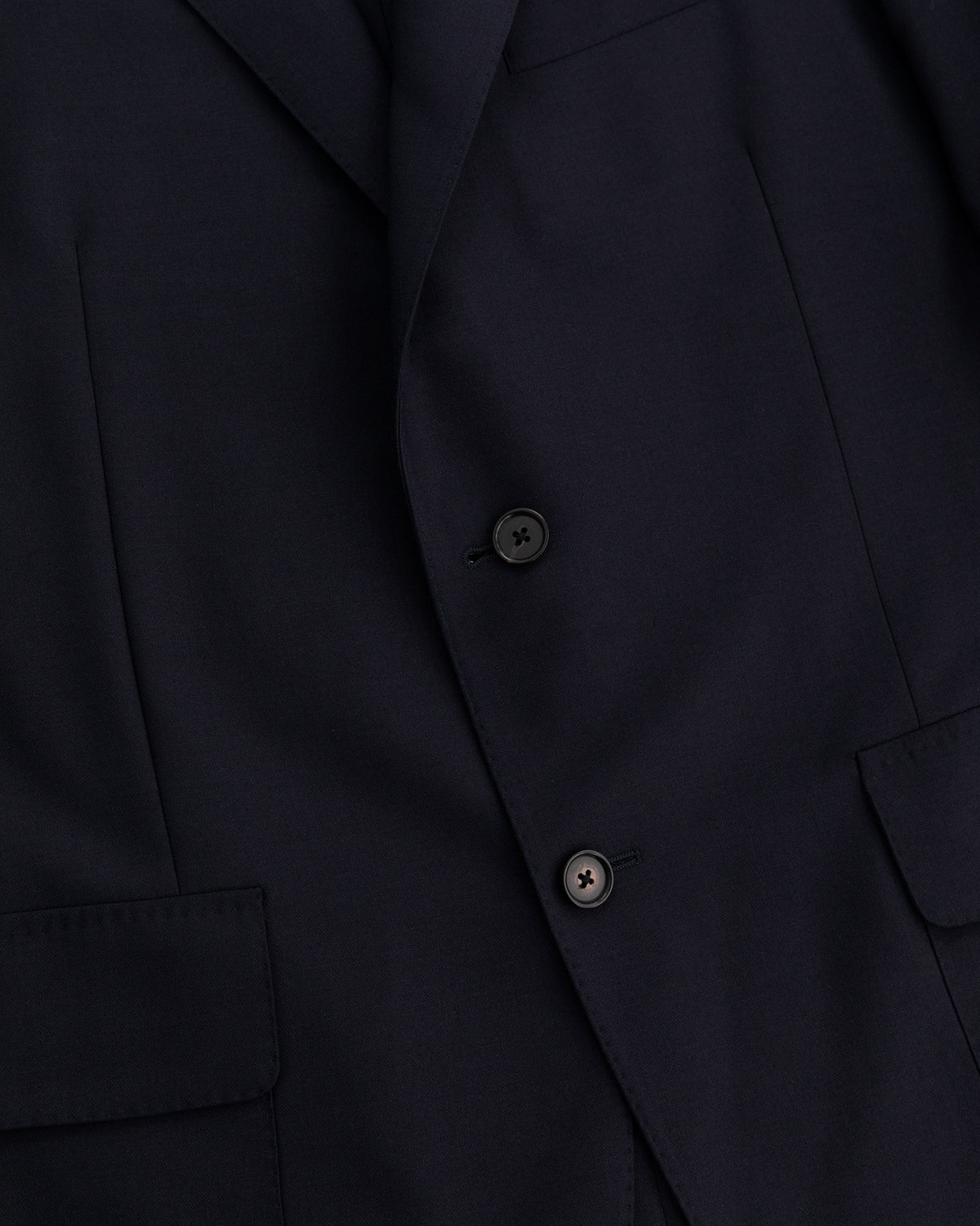 Close-up of the Tropical Wool Suit Jacket in dark navy, showing two buttons, lapel, and front pockets.