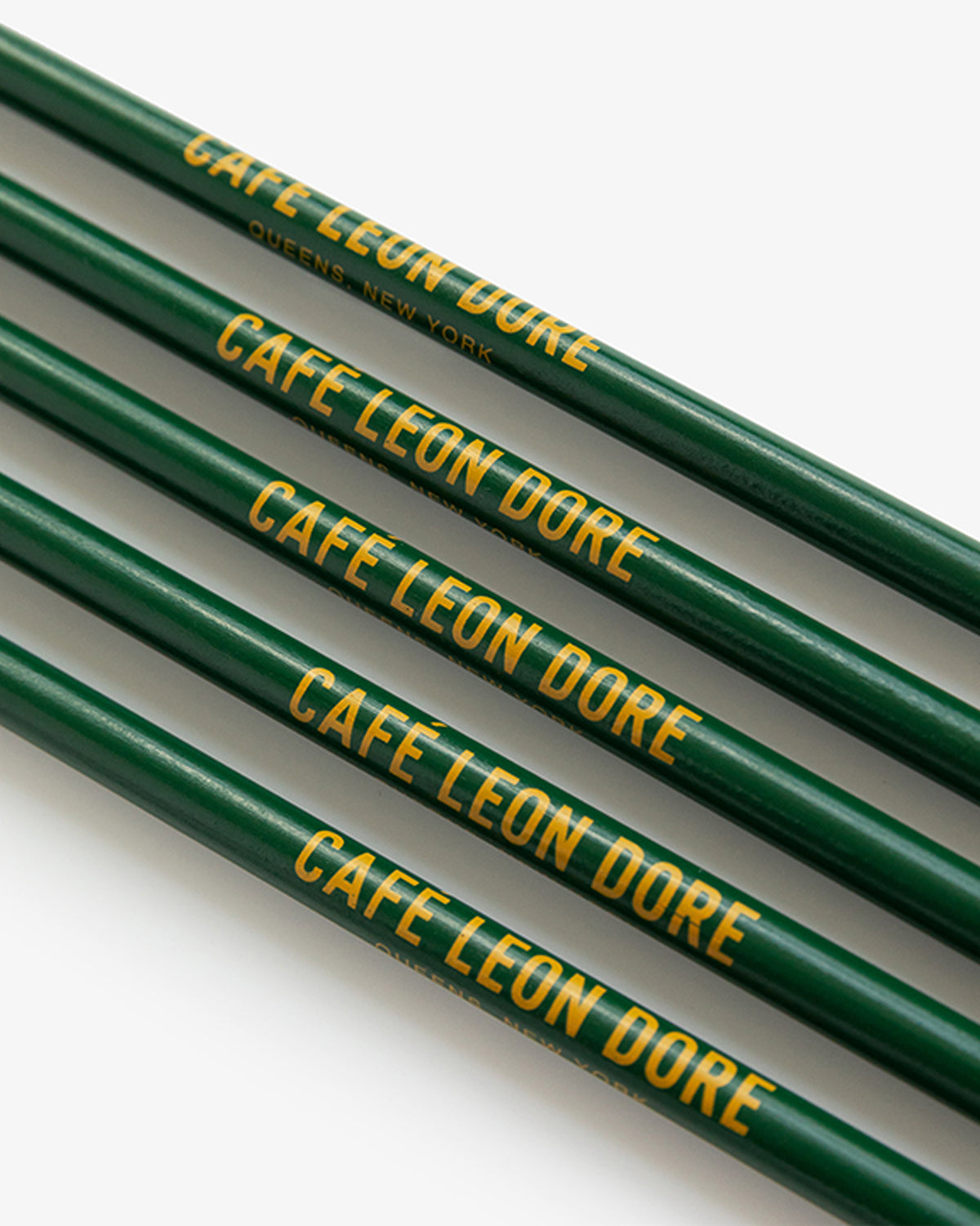 The Café Leon Dore Pencil Pack features four green pencils with yellow text, arranged parallel on a white background.