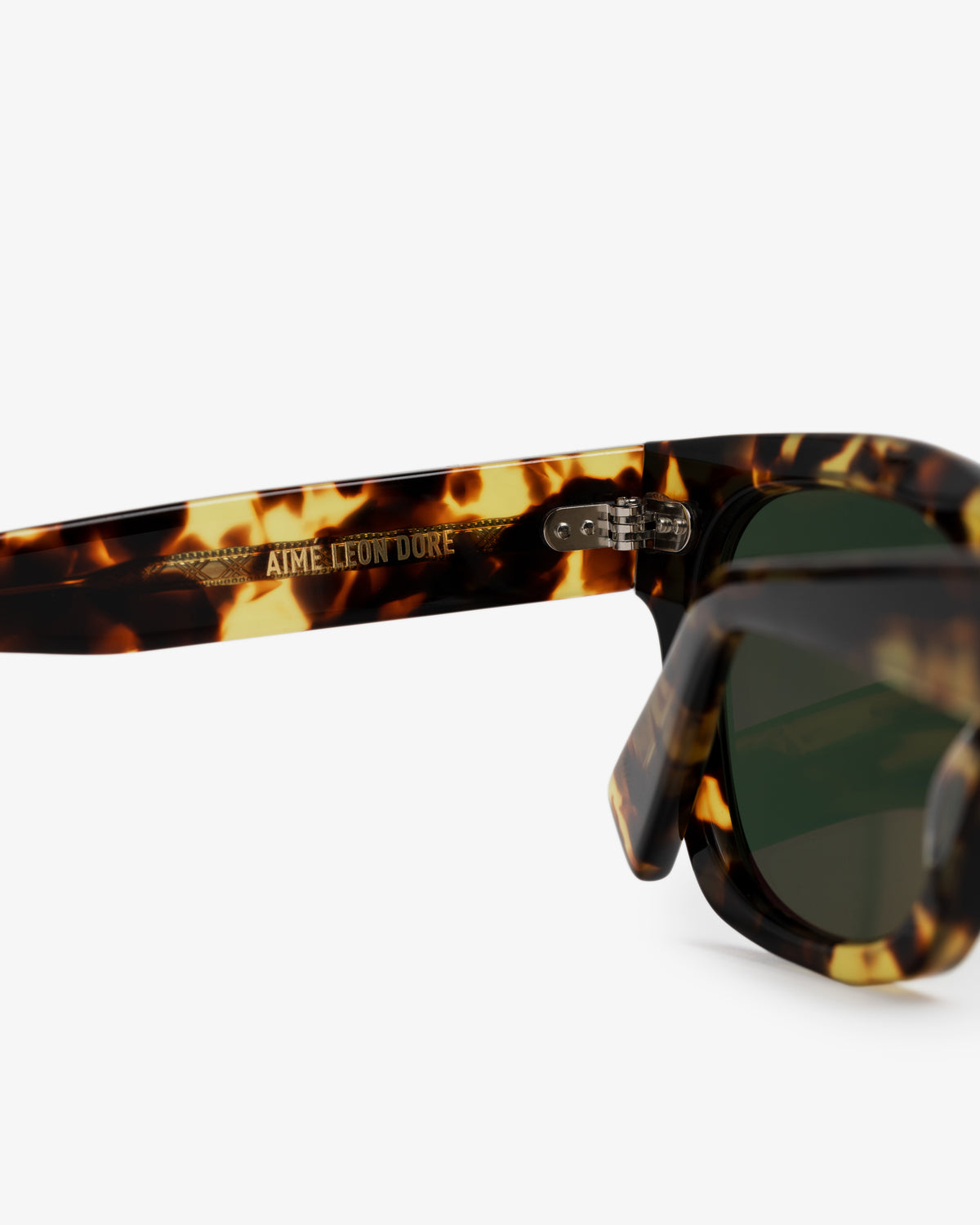 Close-up of Gallo Sunglasses with tortoiseshell frame, green lenses, and Aime Leon Dore etched on the inside arm.