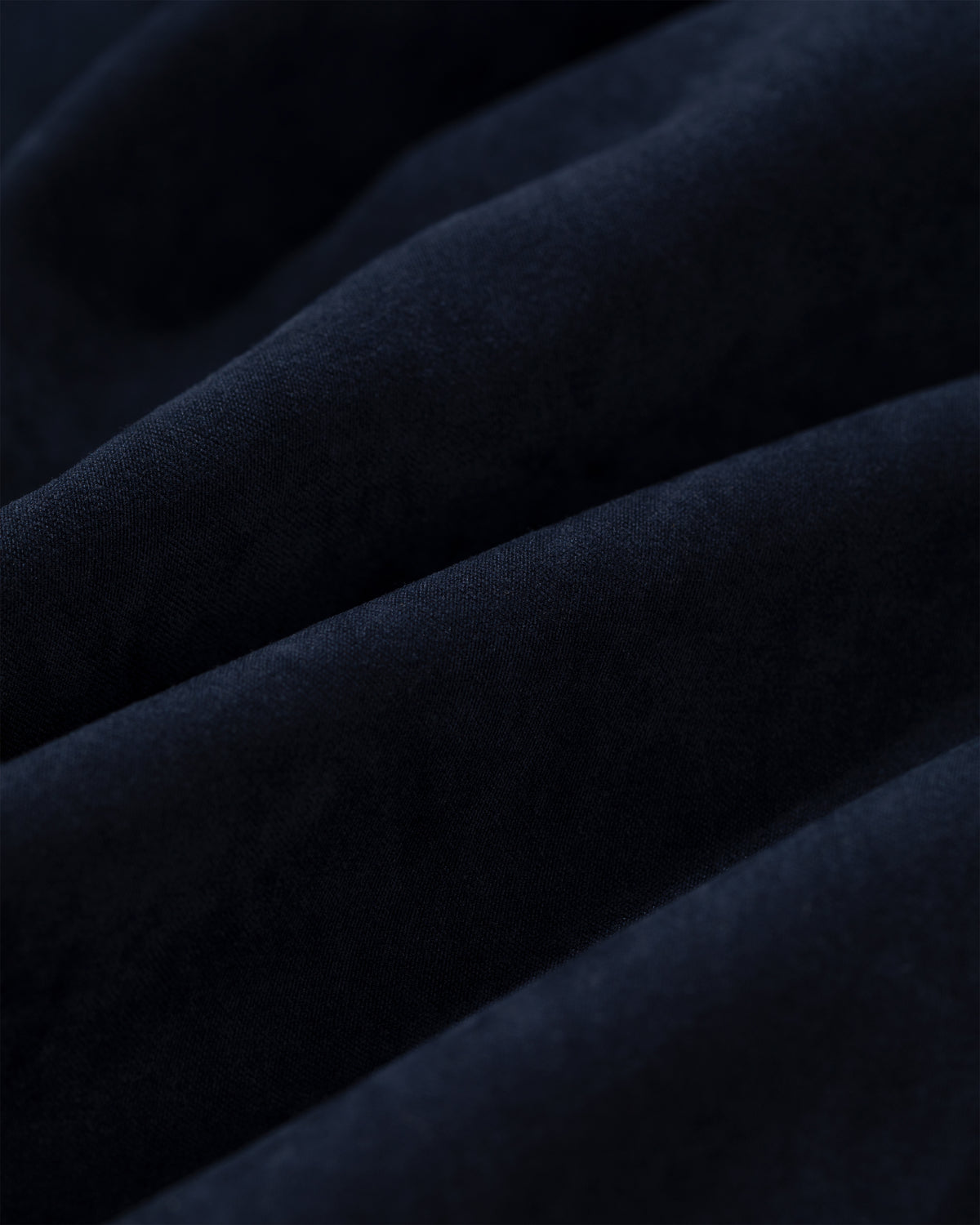 Close-up of soft, dark blue Tropical Wool Elasticated Waist Suit Trouser fabric with gentle, wavy folds.