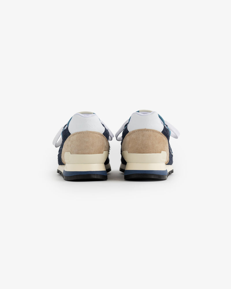 New Balance Made in USA 996 sneakers shown from the back, with navy blue, beige, and white accents on a white background.