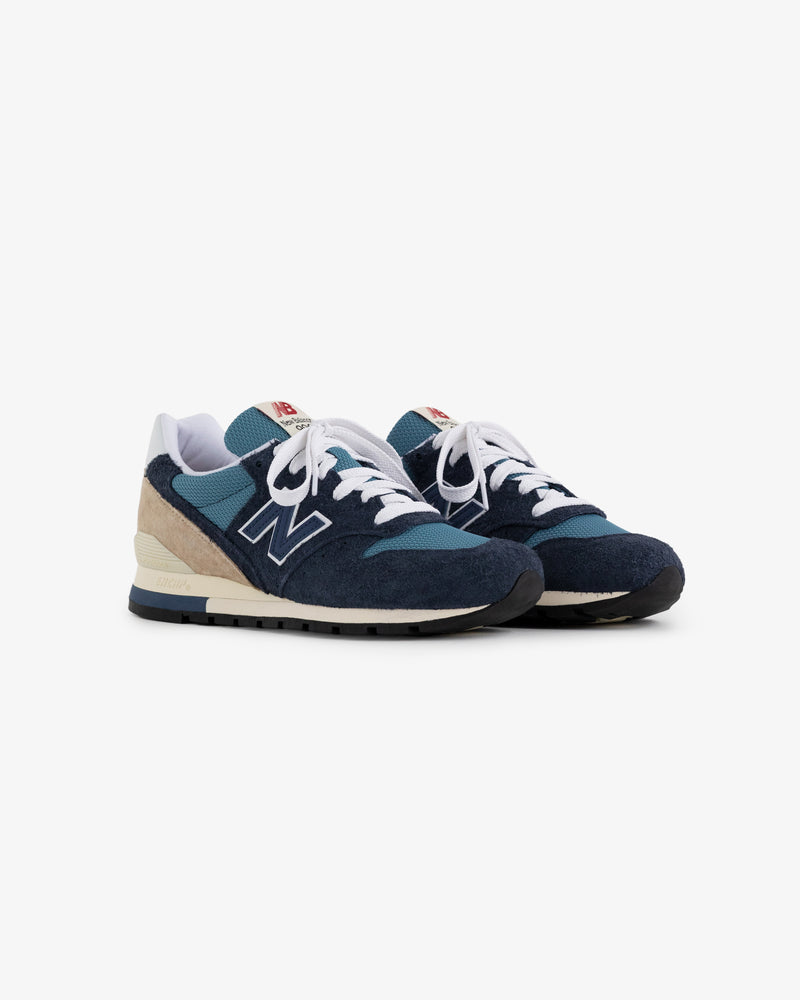 A pair of New Balance Made in USA 996 sneakers in blue and beige with white laces on a white background.