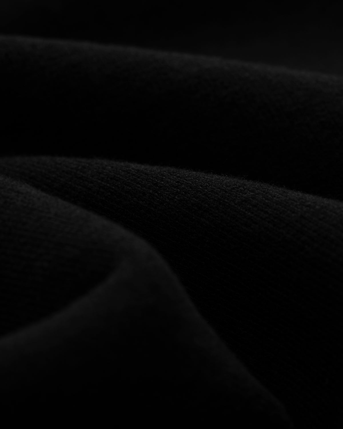 Close-up of the soft black fabric and textured folds of Tonal Logo Sweatshorts in low lighting.