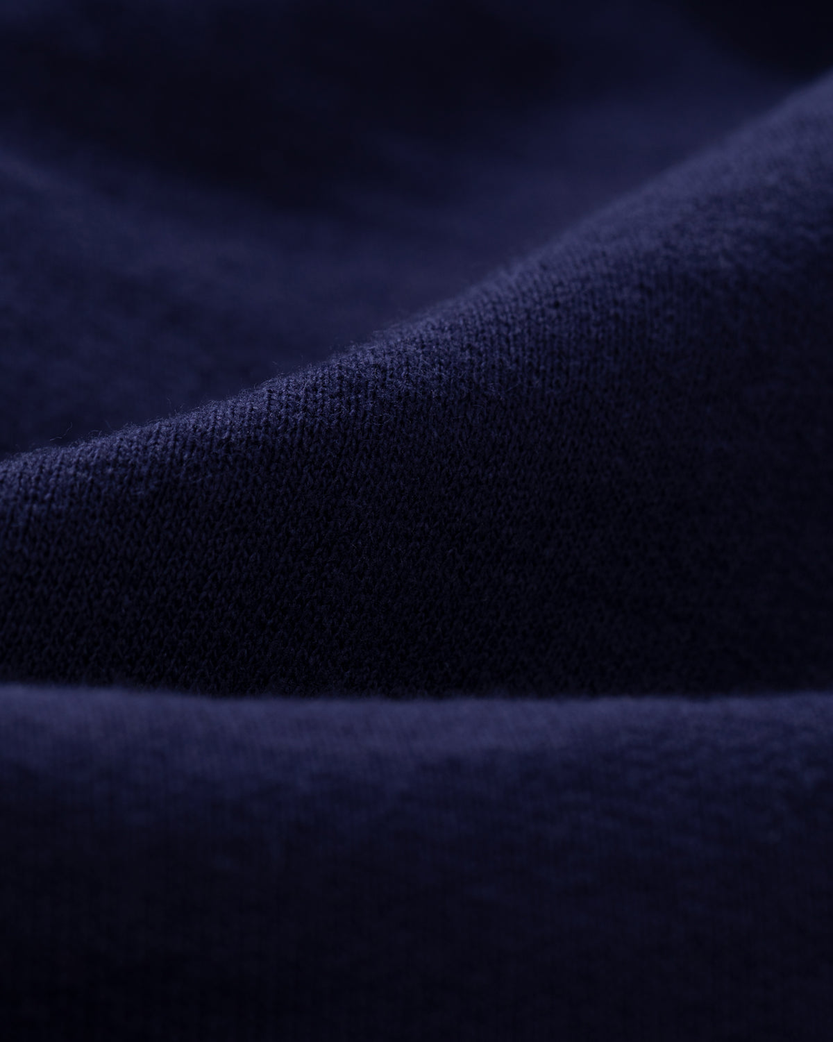 Close-up of Tonal Logo Sweatshorts in dark blue, showing soft textured fabric with gentle folds.