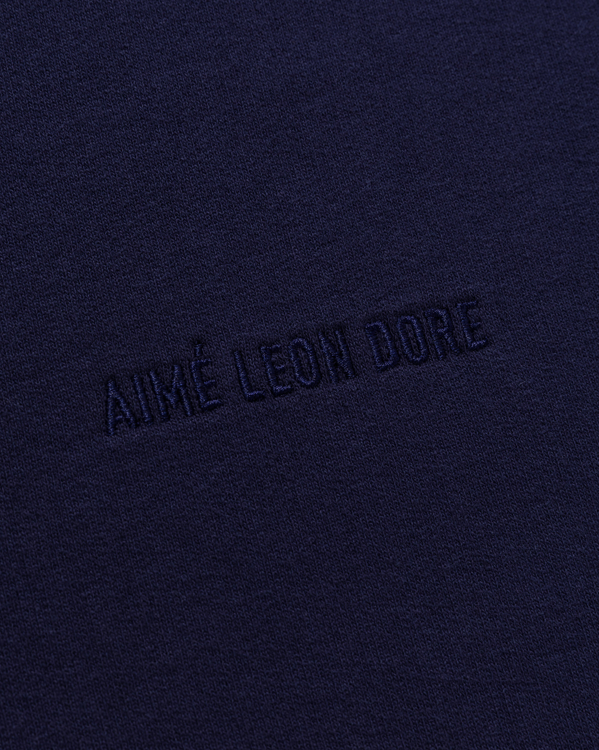 Close-up of dark navy Tonal Logo Sweatshorts with AIMÉ LEON DORE embroidered in matching thread.